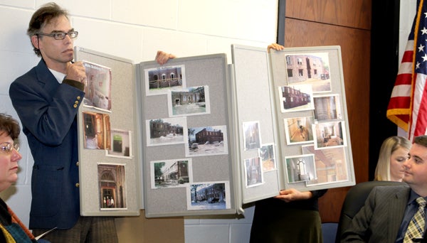 Graham Hatch and his wife, Brenda (hidden from view), hold a collection of photos from a local project that turned an old school into senior citizen housing. The husband and wife have a plan to transform the old Sunbury School, which they own, into senior apartments. Staff Photo by Cal Bryant