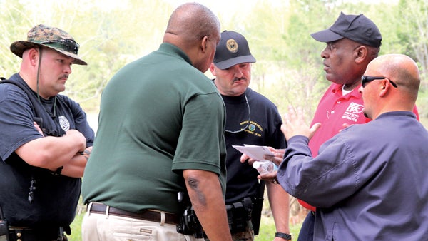 Hertford County Sheriff Juan Vaughan (green shirt) meets with the ranking members of NC PERT along with Brian Parnell (foreground, right) of NC Emergency Management during Monday’s search for a missing Suffolk, VA man. Staff Photo by Cal Bryant 