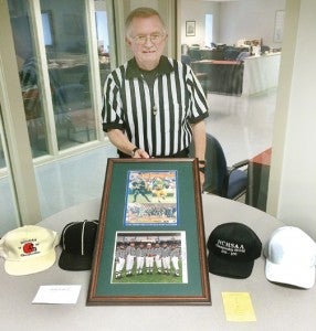 Charles Freeman of Ahoskie displays a framed memento of the 1998 State Football Championship game, one that he officiated, along with the numerous caps he wore during his 43 years as a high school football official. Staff Photo by Caslee Sims