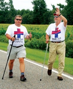 Belhaven Mayor Adam O’Neal (left) flashes the thumbs up sign while author and activist Bob Zellner (right) waves to a passing motorist on Dilday Road in Bertie County Wednesday.  The two men are walking 273 miles from Belhaven to Washington, DC to draw attention to what they consider a health care crisis that threatens the rural Beaufort County coastal community. Staff Photo by Gene Motley