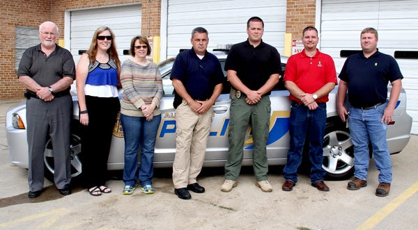 Town of Aulander officials, from left, Ron Poppell, Johnna Browne, Bobbie Parker, Jimmy Barmer and Justin Farmer, join with Brett Thomas and Kevin Stinson (far right), representing Golden Peanut, in front of one of the town’s police cars now equipped with a new computer system purchased through a grant supplied by ADM (the parent company of Golden Peanut). Staff Photo by Cal Bryant