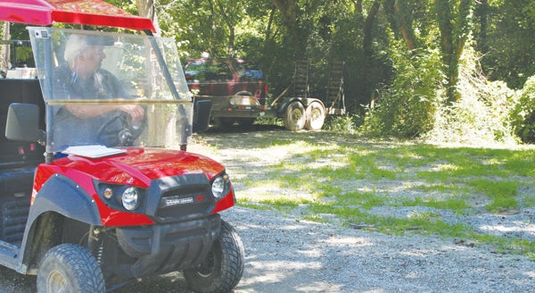 John Yoder sits in his ATV inspecting the area of his property where he alleges Sunland Builders should have graded, seeded, and placed straw to restore the lawn at the site following the installation of the village’s Wastewater Collection System. Staff Photo by Gene Motley
