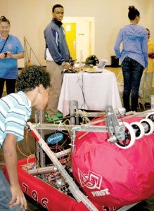 Bertie Middle School student Thomas Bazemore (left, foreground) and his mother, observe the Bertie High STEM school project of Rayshawn Evans (middle) and Kiani Strong (back to camera) that was entered in the high school robotics competition in Raleigh last year. Staff Photo by Gene Motley
