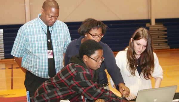 Bertie Middle School STEM teacher Darrell Walker (rear) watches as students (from left) Jai’Kiese Freeman, Zania Newkirk, and Angel Baker program their robot during rehearsal for Saturday’s robotics tournament at Roanoke-Chowan Community College. Staff Photo by Gene Motley