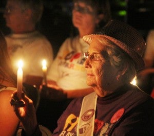 The warm glow of a candle illuminates the face of a cancer survivor during Friday night’s portion of the annual event. Staff Photo by Cal Bryant