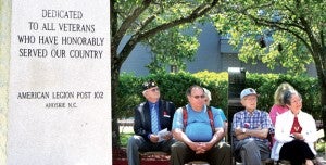 A few of those attending Monday’s tribute in Ahoskie are seated near the memorial monument erected in honor of military veterans at Ahoskie’s No Man’s Land Park. Staff Photo by Gene Motley