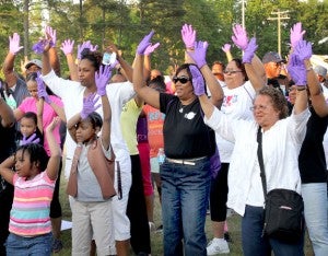 Wearing purple gloves, Relay for Life team members gather in front of the main stage to participate in an upbeat exercise routine. Staff Photo by Cal Bryant