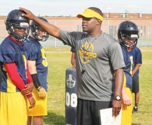 Hertford County football coach Terrance Saxby demonstrates a play to quarterback Christian Folston (left) before the start of spring practice. Staff Photo by Gene Motley 