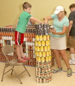 Gina Basnight and Thomas Nelson are shown placing cans of food on the farm silo, part of a “hunger awareness” project by members of Ahoskie United Methodist Church. Staff Photo by Cal Bryant
