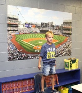 This youngster stands in front of a Yankee Stadium poster that covers a portion of one wall inside a sports-themed classroom. Staff Photo by Cal Bryant
