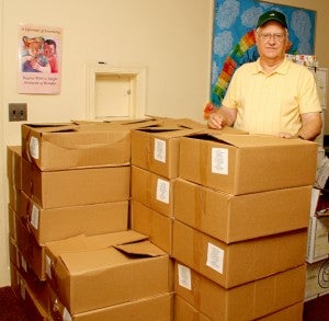 Food Pantry volunteer Bill Arrington stands with the boxes, each containing six bags of food items, that are ready to be delivered to four schools in Hertford County. Staff Photo by Cal Bryant