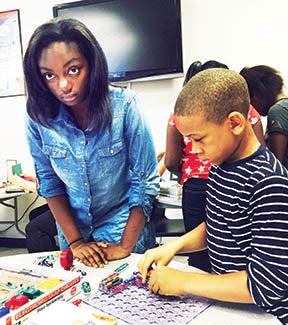 Volunteer Makayla Norman (left) assists Jordan Staton (right) in constructing a circuit board with snap circuits during Maker Faire at Hertford County Early College High School.