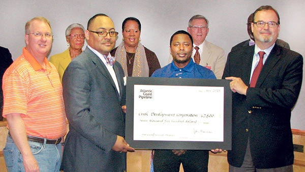 Rev. Anthony Rawlings (foreground, second from left) and Christian Martin (third from left) of Creek Development Corporation accept a $7,500 grant from Bruce McKay (right), representing the Atlantic Coast Pipeline Community Investment Program. At left is Michael Wray, who represents Northampton and Halifax counties in the NC House of Representatives. | Photo by Keith Hoggard