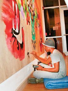 Second year RCCC Art student Brandon Sessoms of Ahoskie adds to a colorful mural on a hallway at the local community college.